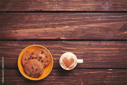 Cookie and cup of coffee on wooden table.