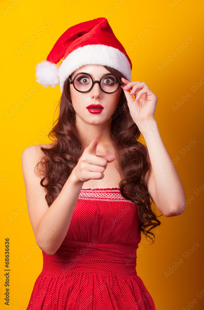 Beautiful brunette girl in christmas hat with glasses on yellow Beautiful brunette girl in christmas hat with glasses on yellow