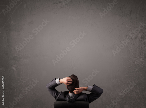 Businessman sitting in front of a wall with copy space