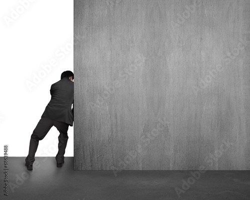 businessman pushing concrete wall away