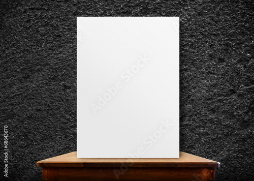 blank poster frame on wood table at black stone wall,perspective