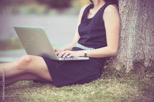 Beautiful young woman using laptop in park