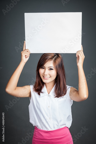 Asian girl hold blank sign over her head and smile