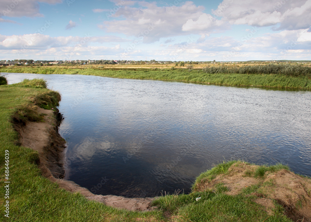 View to river with reflections and blue cloudy sky View to river with reflections and blue cloudy sky