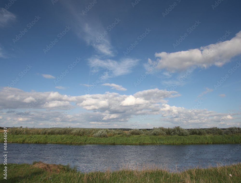 View to river with reflections and blue cloudy sky