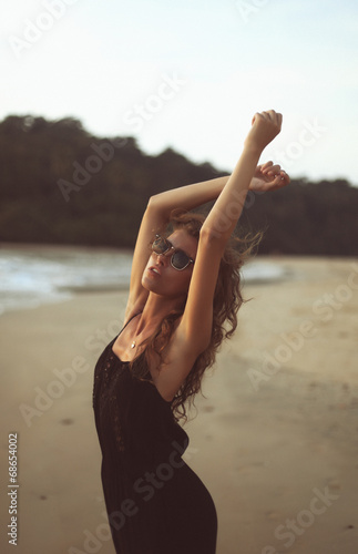 Young beautiful curly woman in sunglasses at the seaside photo