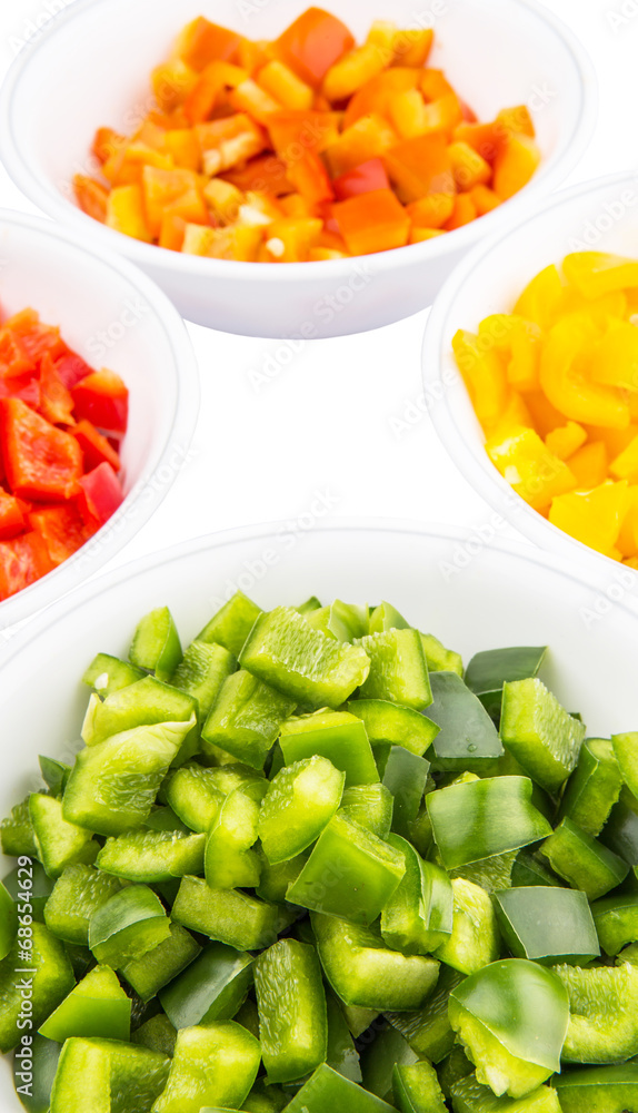 Colorful chopped capsicums in white bowls over white background Colorful chopped capsicums in white bowls over white background
