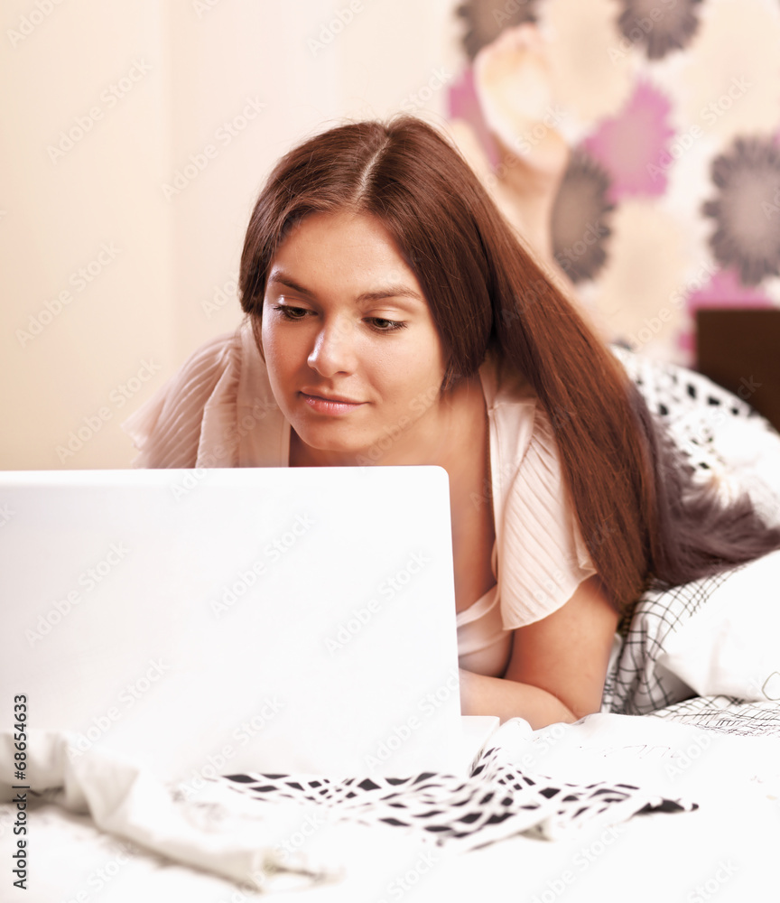 Young woman lying on the bed with laptop Young woman lying on the bed with laptop