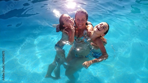 Foto Contraluz de madre con hijos en la piscina