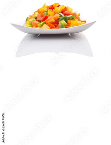 Mix colorful chopped capsicums in a plate over white background photo