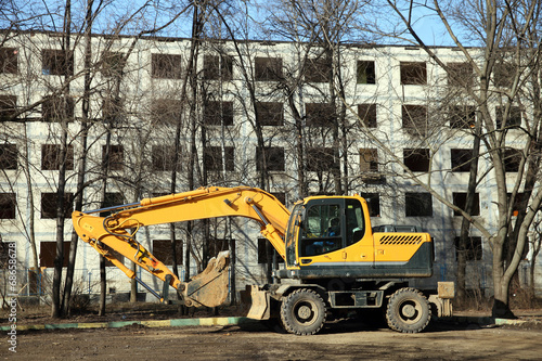 The yellow excavator against empty building