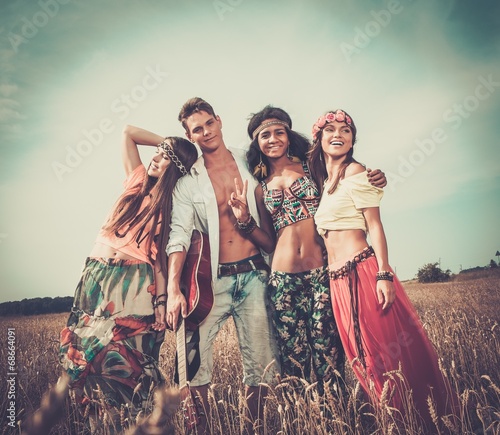 Multi-ethnic hippie friends with guitar in a wheat field