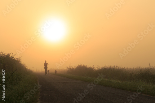 Woman and her dogs running in the fog.