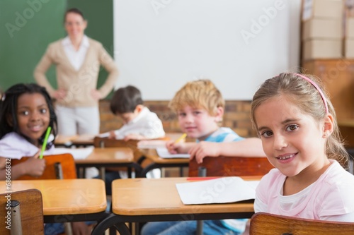 Pupils and teacher smiling at camera in classroom