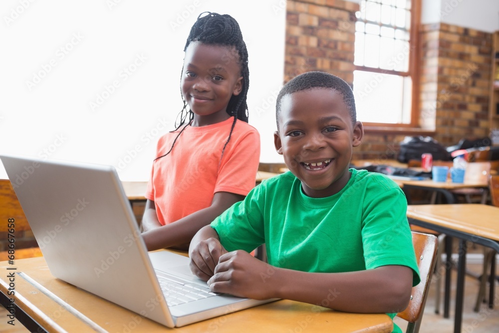 Cute pupils using laptop in classroom Cute pupils using laptop in classroom