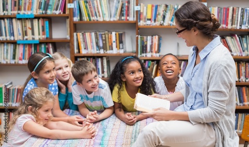 Cute pupils and teacher reading in library