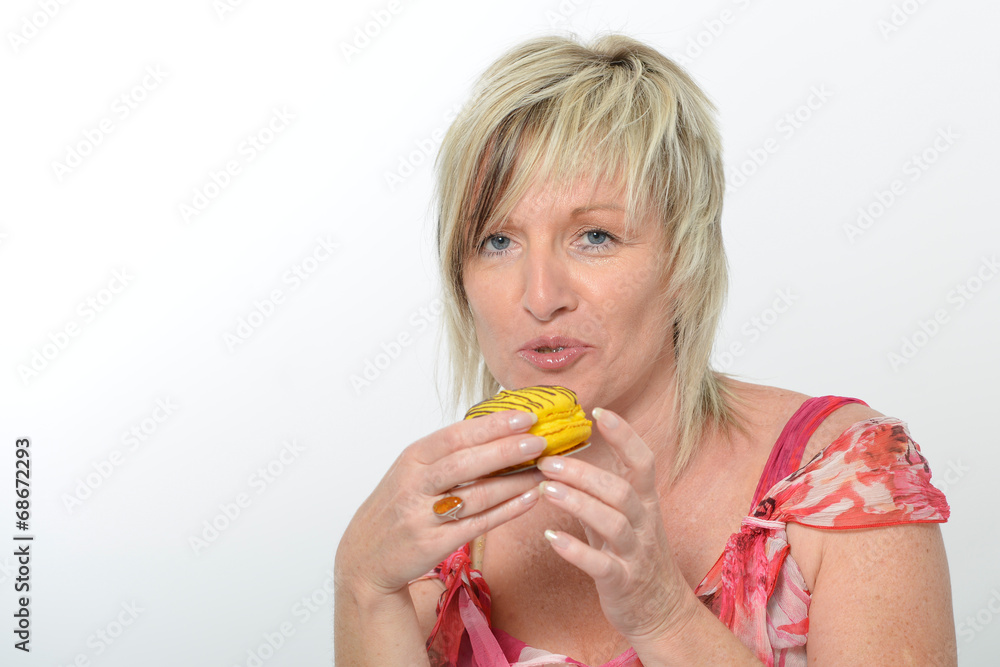 Beautiful senior woman smiling in pink suit eating yellow macaro Beautiful senior woman smiling in pink suit eating yellow macaro