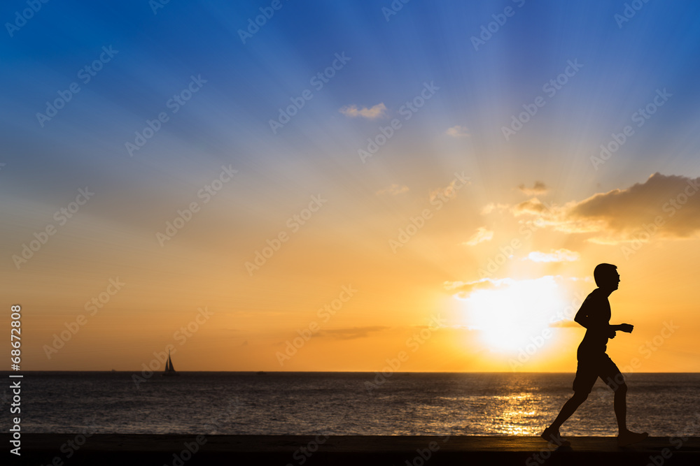 Silhouette of jogging man at the beach with sunset background