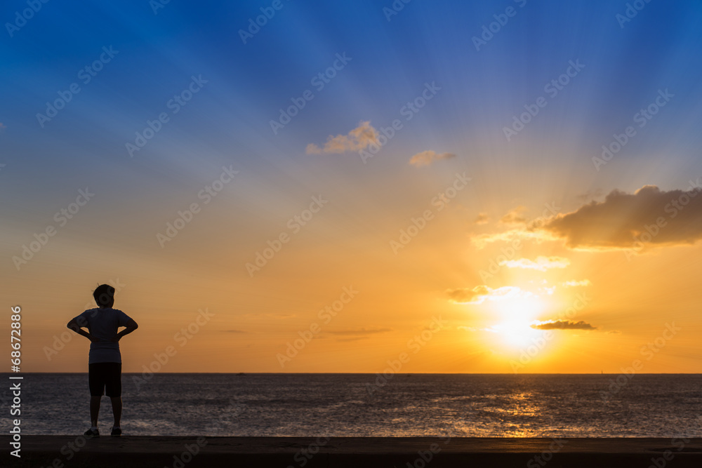Silhouette of women standing at the beach with sunset background