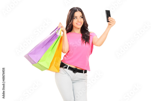 Beautiful girl holding shopping bags and taking selfie