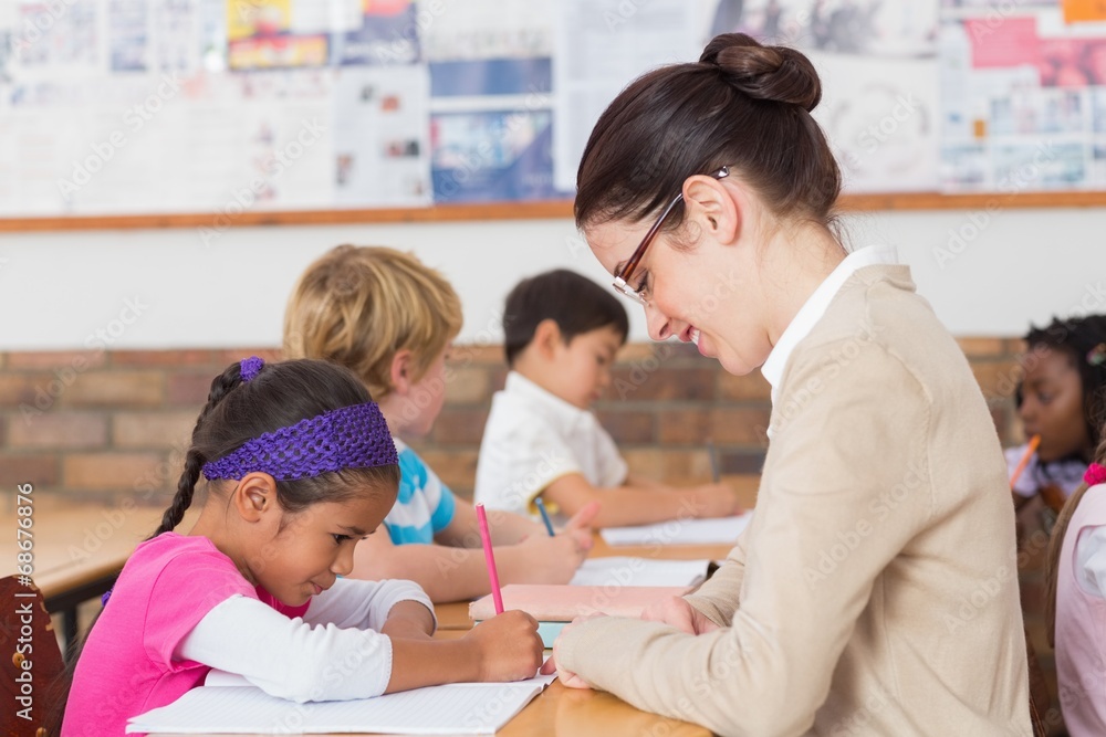 Pretty teacher helping pupil in classroom Pretty teacher helping pupil in classroom