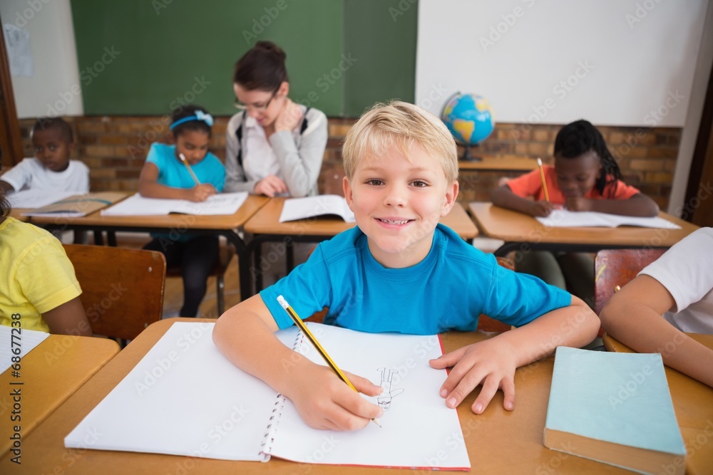 Cute pupils writing at desk in classroom Cute pupils writing at desk in classroom