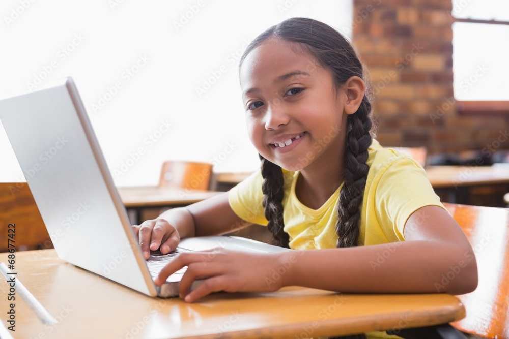 Cute little pupil looking at laptop in classroom Cute little pupil looking at laptop in classroom