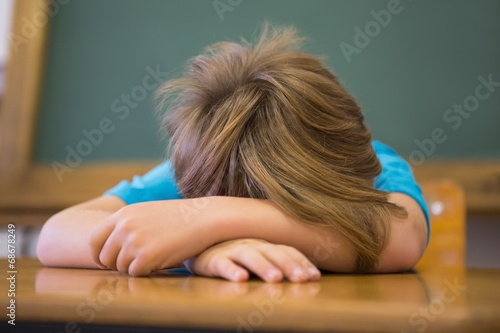 Canvas Print Sleepy pupil napping at desk in classroom