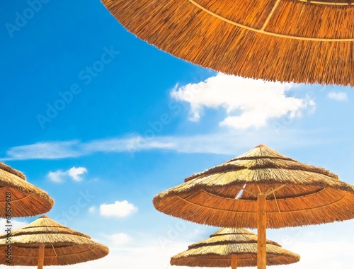 Fototapeta Naklejka Na Ścianę i Meble -  Beach umbrellas on blue sky background with clouds