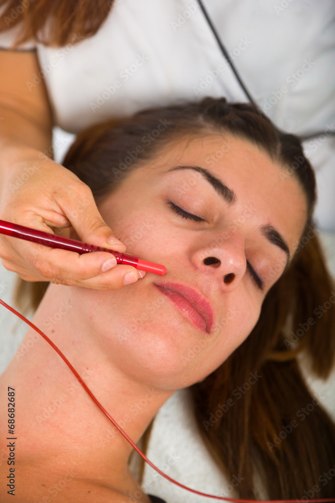 Attractive female patient receiving electro acupuncture on face