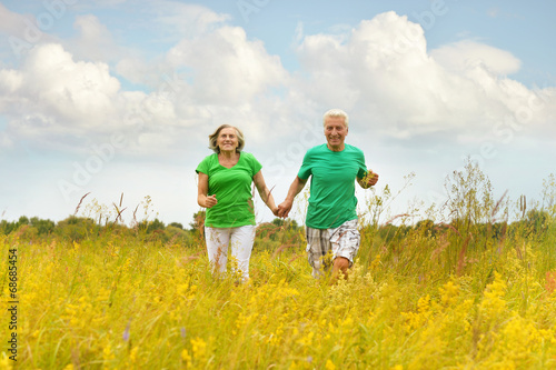Senior couple running in summer field