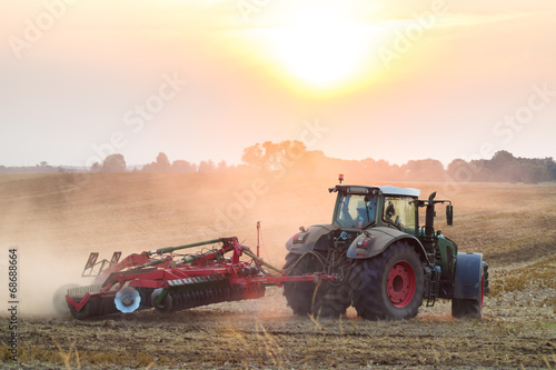 Fototapeta Naklejka Na Ścianę i Meble -  Tractor in sunrise plowing the field 