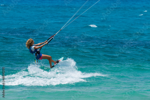 Photography A young woman kite-surfer rides in greenish-blue sea