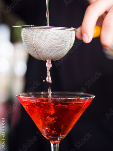 Bartender pooring cocktail into Martini glass photo