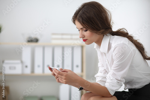Businesswoman sending message with smartphone sitting in the