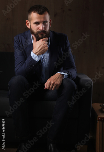 Businessman sitting the sofa in office lobby, isolated on dark