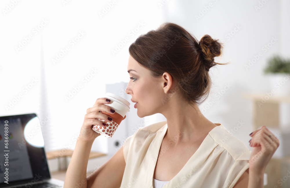 Attractive woman sitting at desk in office, working with laptop Attractive woman sitting at desk in office, working with laptop