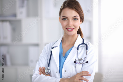 Portrait of young woman doctor with white coat standing in
