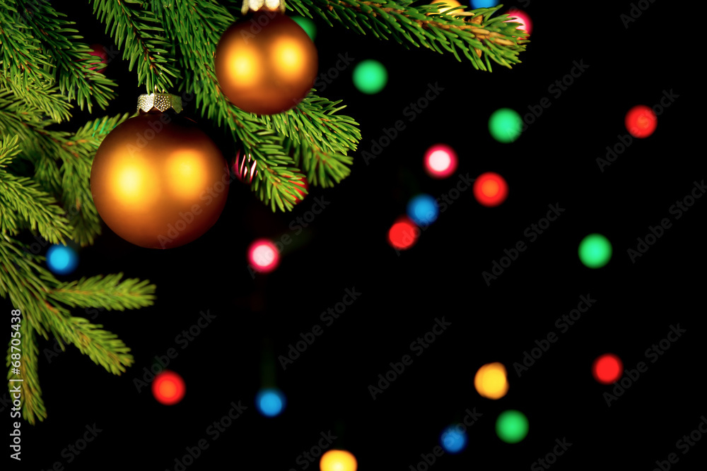 Christbaumkugeln vor schwarzem Hintergrund mit bunten Lichtern