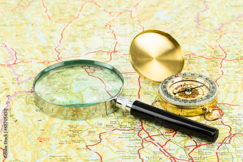 Retro compass and magnifier on a road map