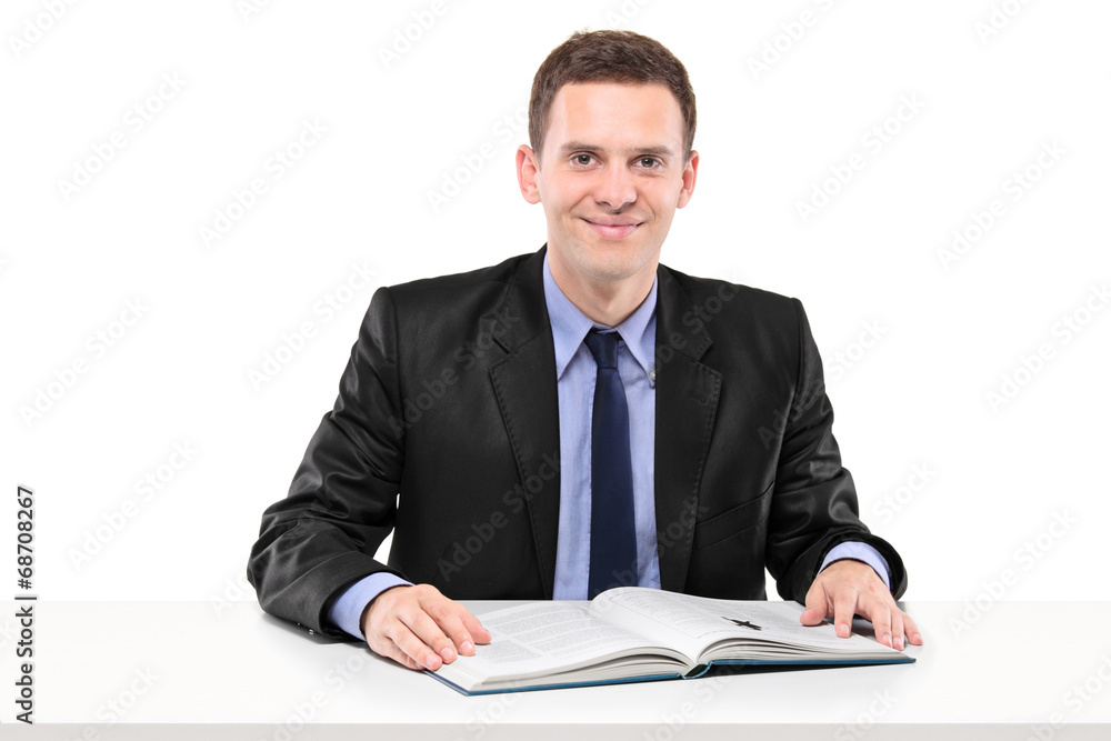 Young businessman reading a book seated at a table Young businessman reading a book seated at a table