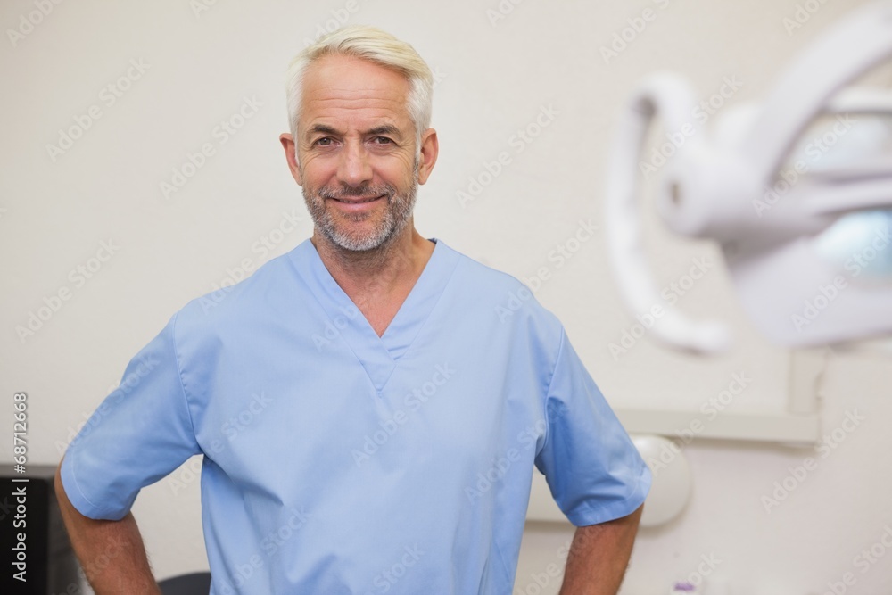 Fototapeta premium Dentist smiling at camera in blue scrubs