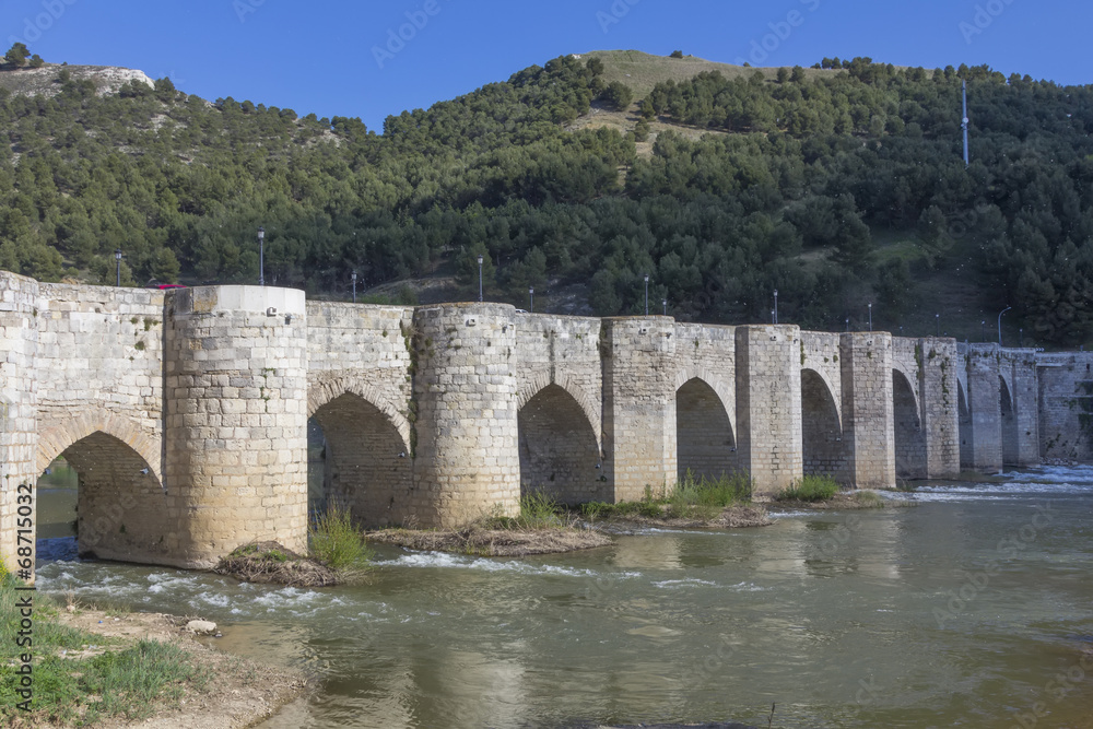 Old stone bridge block with arches and water
