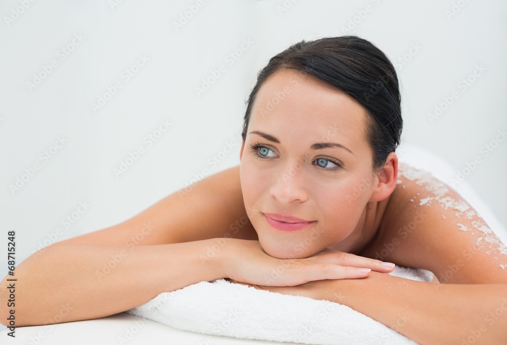 Peaceful brunette lying with salt scrub on back Peaceful brunette lying with salt scrub on back