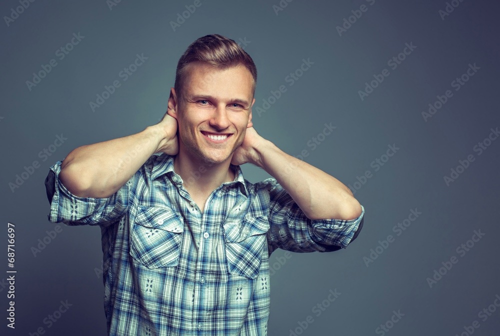 Smiling young man standing against gray background dressed in bl Smiling young man standing against gray background dressed in bl