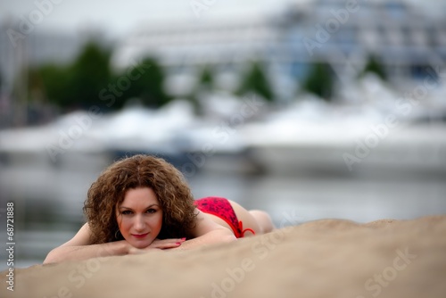 Young woman with curling hair lies on a beach