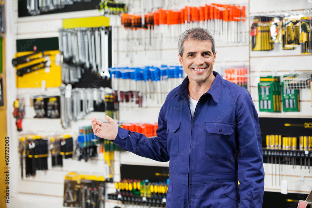 Worker In Overalls Gesturing In Hardware Store Worker In Overalls Gesturing In Hardware Store