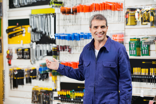 Worker In Overalls Gesturing In Hardware Store