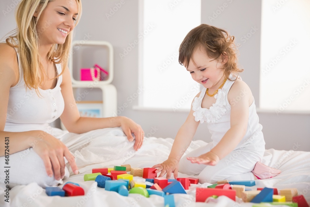 Mother and daughter playing with building blocks on bed Mother and daughter playing with building blocks on bed