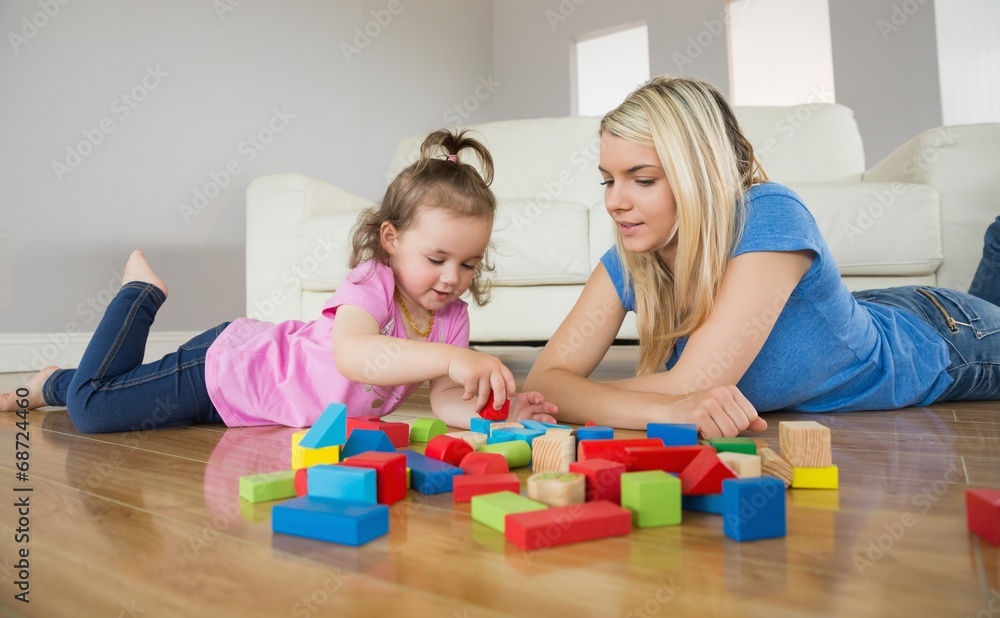 Mother and daughter playing with building blocks on floor Mother and daughter playing with building blocks on floor